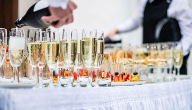 Stylish champagne glasses and food appetizers on table at weddin